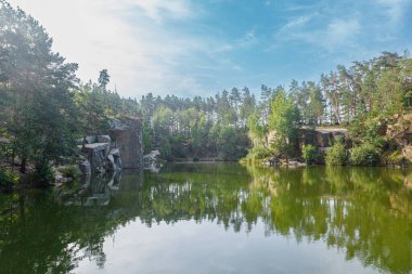 Üzerinde mavi gökyüzü olan kuğuların yüzdüğü güzel bir göl.