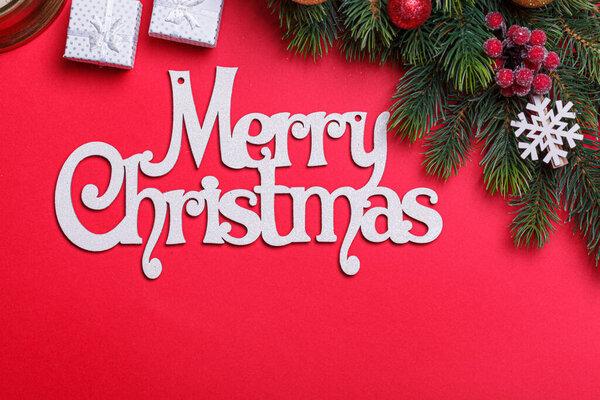 beautiful branches of a Christmas tree with cones and toys on a red background with the inscription Merry Christmas close-up