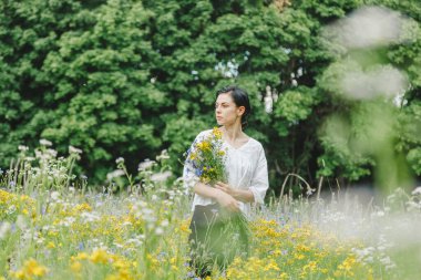 Yaz tarlalarının arasında kır çiçekleriyle güzel bir kız.