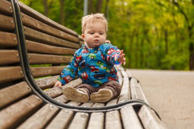Parkta bir bankta sabun köpüğü yakalayan küçük bir çocuğun portresi.