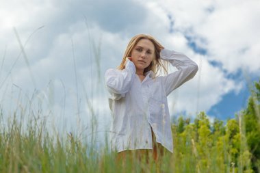 Beyaz gömlekli ve turuncu etekli güzel kız mavi gökyüzüne ve bulutlara karşı