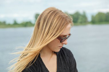 Nehrin arka planında siyah elbiseli güzel bir kız. Mavi gökyüzü ve bulutlarla çevrili bir deniz.