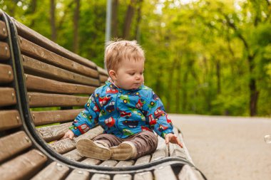 Parkta bir bankta sabun köpüğü yakalayan küçük bir çocuğun portresi.