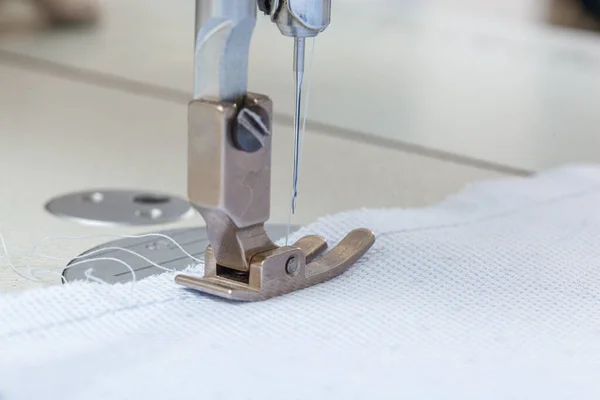 Sewing machine needle with thread and fabric close-up