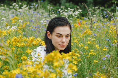 Yaz tarlalarının arasında kır çiçekleriyle güzel bir kız.
