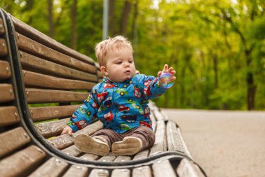 Parkta bir bankta sabun köpüğü yakalayan küçük bir çocuğun portresi.