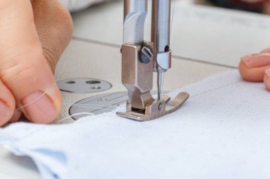 İşinin ehli bir terzinin kadın elleri, dikiş makinesi iğnesi yakın plan.