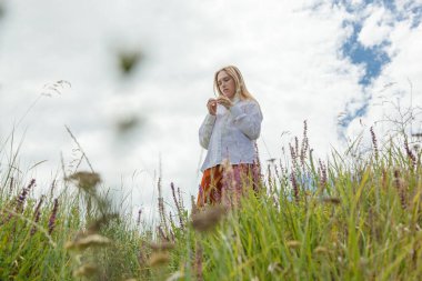 Beyaz gömlekli ve turuncu etekli güzel kız mavi gökyüzüne ve bulutlara karşı