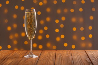 Ahşap arka planda şampanyalı bardaklar yakın plan ışıkların sahte arka planına karşı.