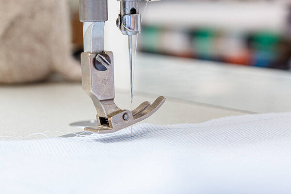 Игла швейной машинки с ниткой и ткань крупным планом