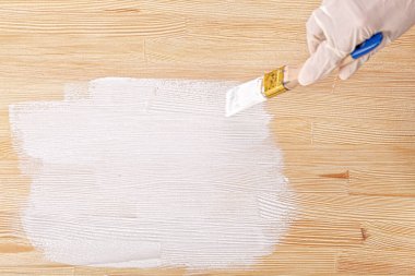 white paint with a brush painting a wooden background with texture close up