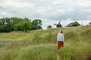 Beyaz gömlekli ve turuncu etekli güzel kız mavi gökyüzüne ve bulutlara karşı