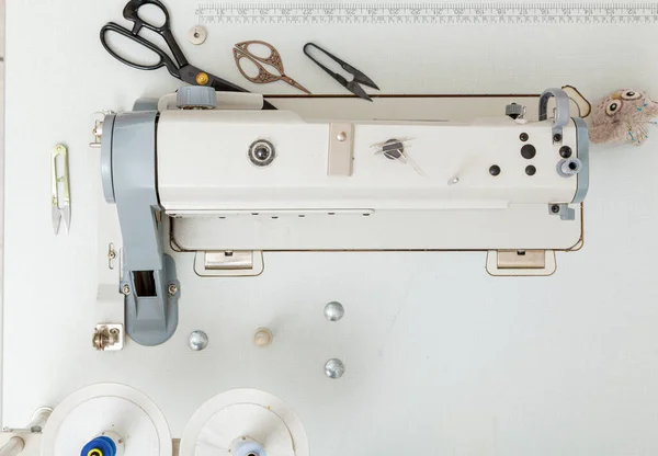 Top view sewing machine with sewing tools, scissors, thread close-up