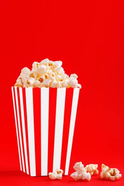 Kırmızı arka planda patlamış mısırlı cam.