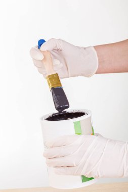 hand with a brush and a can of paint on a white background close-up