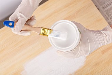 white paint with a brush painting a wooden background with texture close up