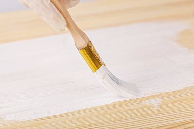 white paint with a brush painting a wooden background with texture close up
