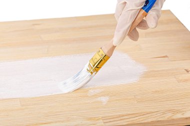 white paint with a brush painting a wooden background with texture close up