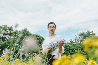 Yaz tarlalarının arasında kır çiçekleriyle güzel bir kız.