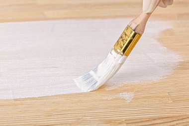 white paint with a brush painting a wooden background with texture close up