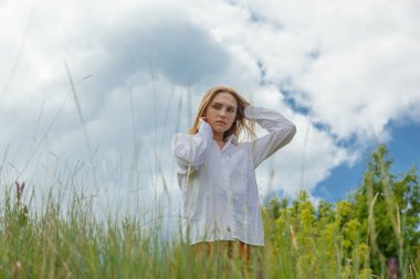 Beyaz gömlekli ve turuncu etekli güzel kız mavi gökyüzüne ve bulutlara karşı