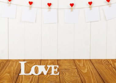 white pieces of paper on clothespins with a heart on a wooden background, a wooden inscription I love you close-up