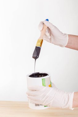hand with a brush and a can of paint on a white background close-up