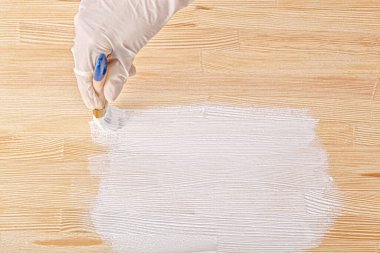 white paint with a brush painting a wooden background with texture close up