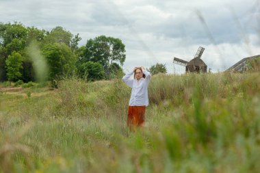 Beyaz gömlekli ve turuncu etekli güzel kız mavi gökyüzüne ve bulutlara karşı