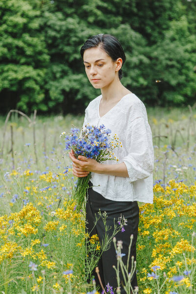 Beautiful girl among the summer field with wildflowers close-up