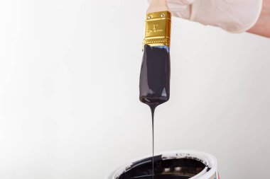 hand with a brush and a can of paint on a white background close-up