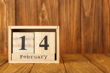white pieces of paper on clothespins with a heart on a wooden background, calendar February 14 close-up