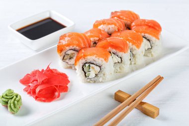 Sushi with salmon on a white plate with wasabi, ginger, soy, chopsticks on a white background close-up
