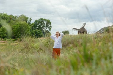 Beyaz gömlekli ve turuncu etekli güzel kız mavi gökyüzüne ve bulutlara karşı
