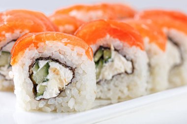 Sushi with salmon on a white plate with wasabi, ginger, soy, chopsticks on a white background close-up