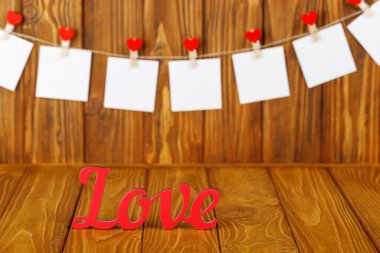 white pieces of paper on clothespins with a heart on a wooden background, a wooden inscription I love you close-up