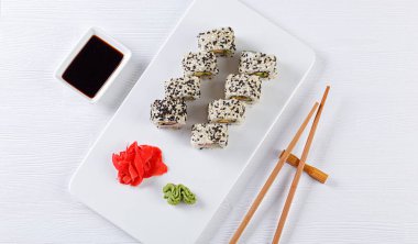 Sushi with salmon on a white plate with wasabi, ginger, soy, chopsticks on a white background close-up