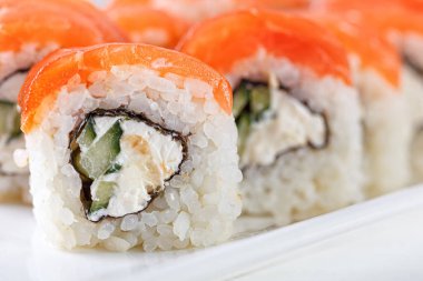 Sushi with salmon on a white plate with wasabi, ginger, soy, chopsticks on a white background close-up