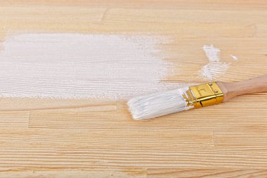 white paint with a brush on a wooden background with texture close-up