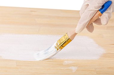 white paint with a brush painting a wooden background with texture close up