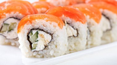 Sushi with salmon on a white plate with wasabi, ginger, soy, chopsticks on a white background close-up