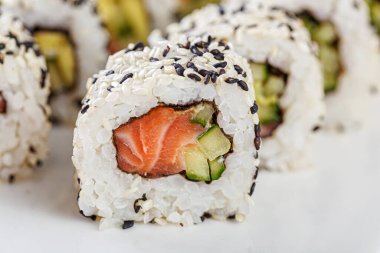 Sushi with salmon on a white plate with wasabi, ginger, soy, chopsticks on a white background close-up