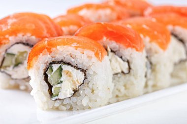 Sushi with salmon on a white plate with wasabi, ginger, soy, chopsticks on a white background close-up