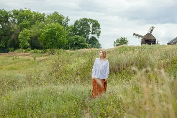 Beyaz gömlekli ve turuncu etekli güzel kız mavi gökyüzüne ve bulutlara karşı