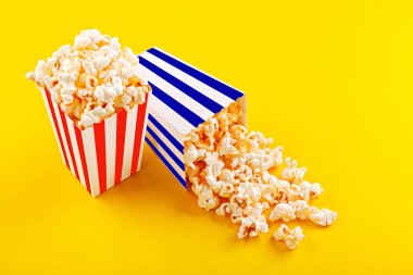 Glass with popcorn on a yellow background close-up
