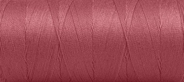 Texture of threads in a spool of red color on a white background close-up