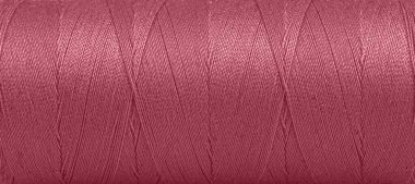 Texture of threads in a spool of red color on a white background close-up