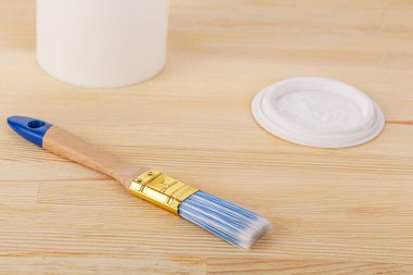 white paint with a brush on a wooden background with texture close-up