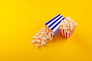 Glass with popcorn on a yellow background close-up