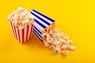 Glass with popcorn on a yellow background close-up